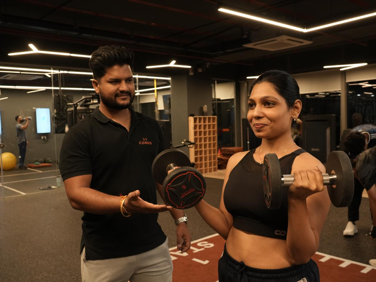 COREO coach guiding a member through dumbbell training