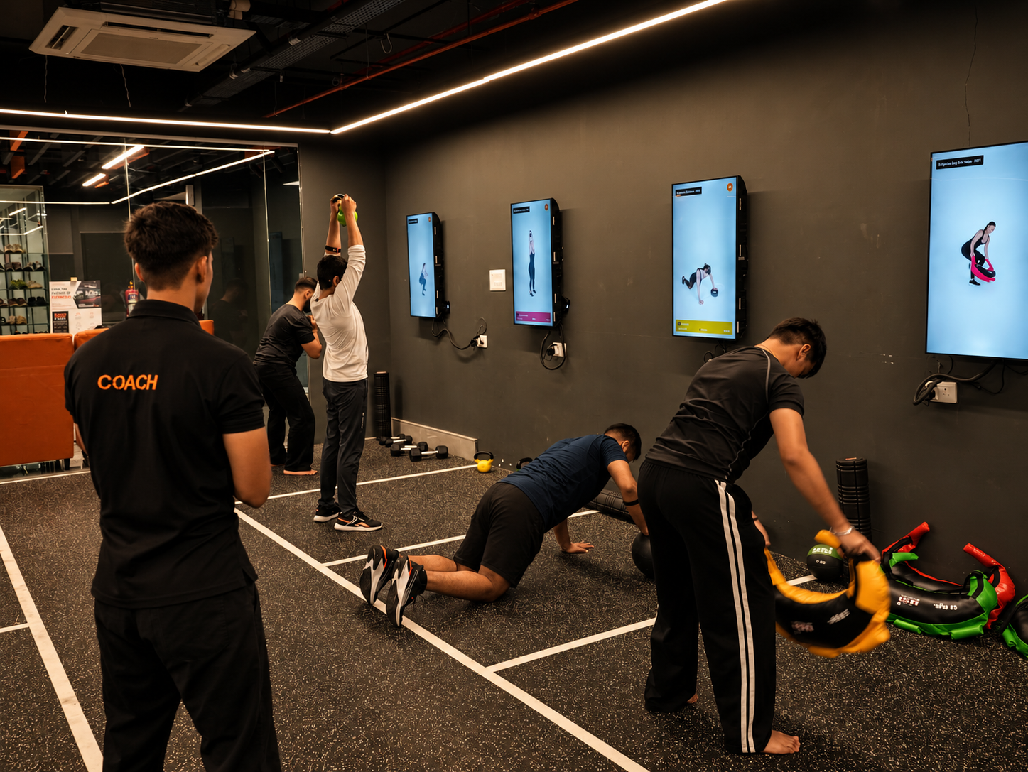 COREO coach watches members work through a group training circuit