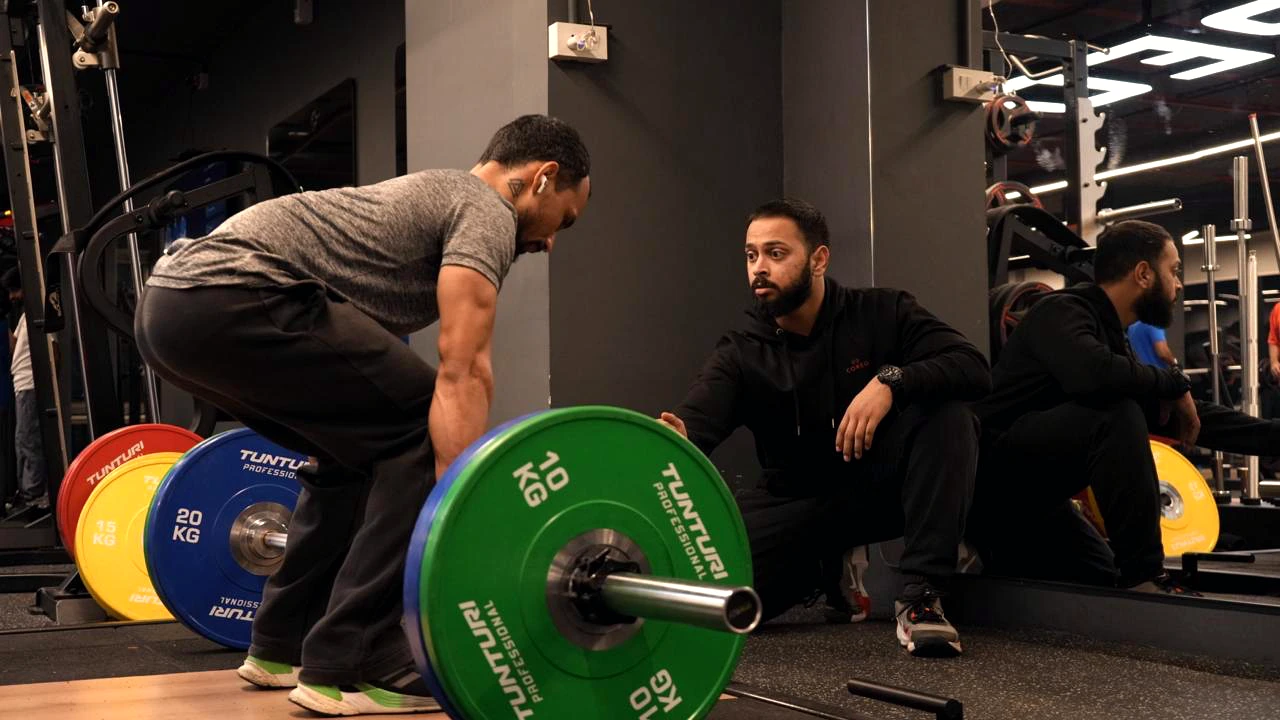 COREO coach guiding a member through a barbell lift